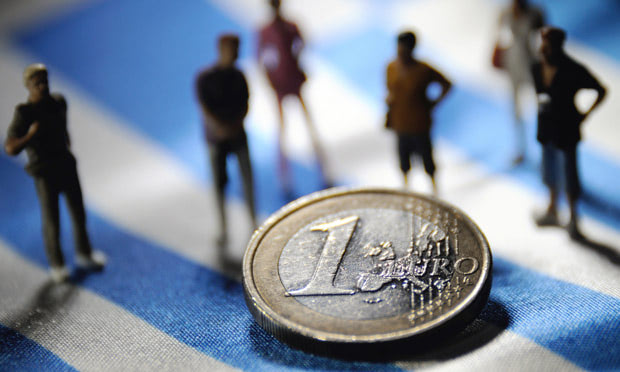 Figurines and a euro on a Greek flag Figurines and a euro on a Greek flag
