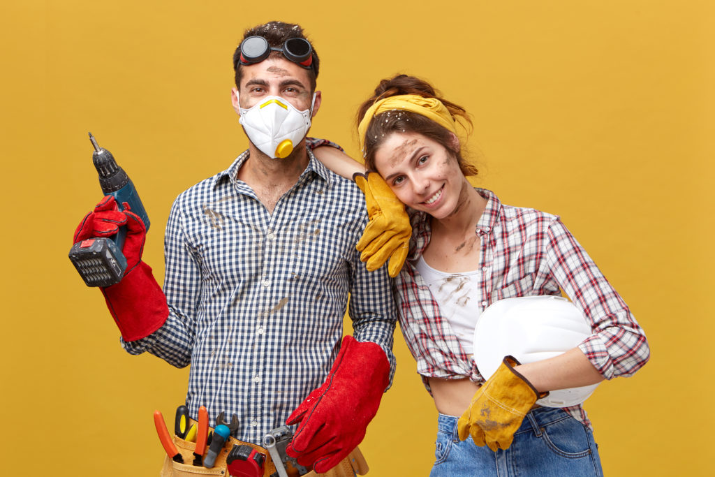 Beautiful female housewife helping her husband with construction wearing checkered shirt holding white helmet leaning at his shoulder having good mood being glad to help him. People and relationships prestamos para reformas integrales