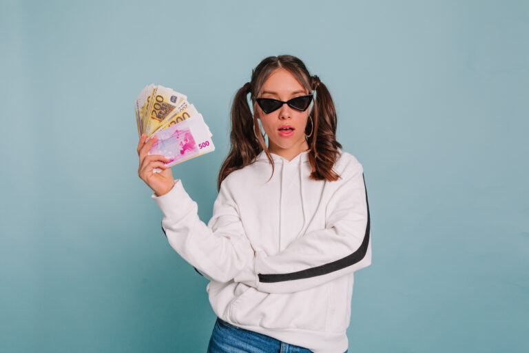 Una chica sosteniendo unos billetes en la mano que ha ganado con los intereses que le ha pagado su banco