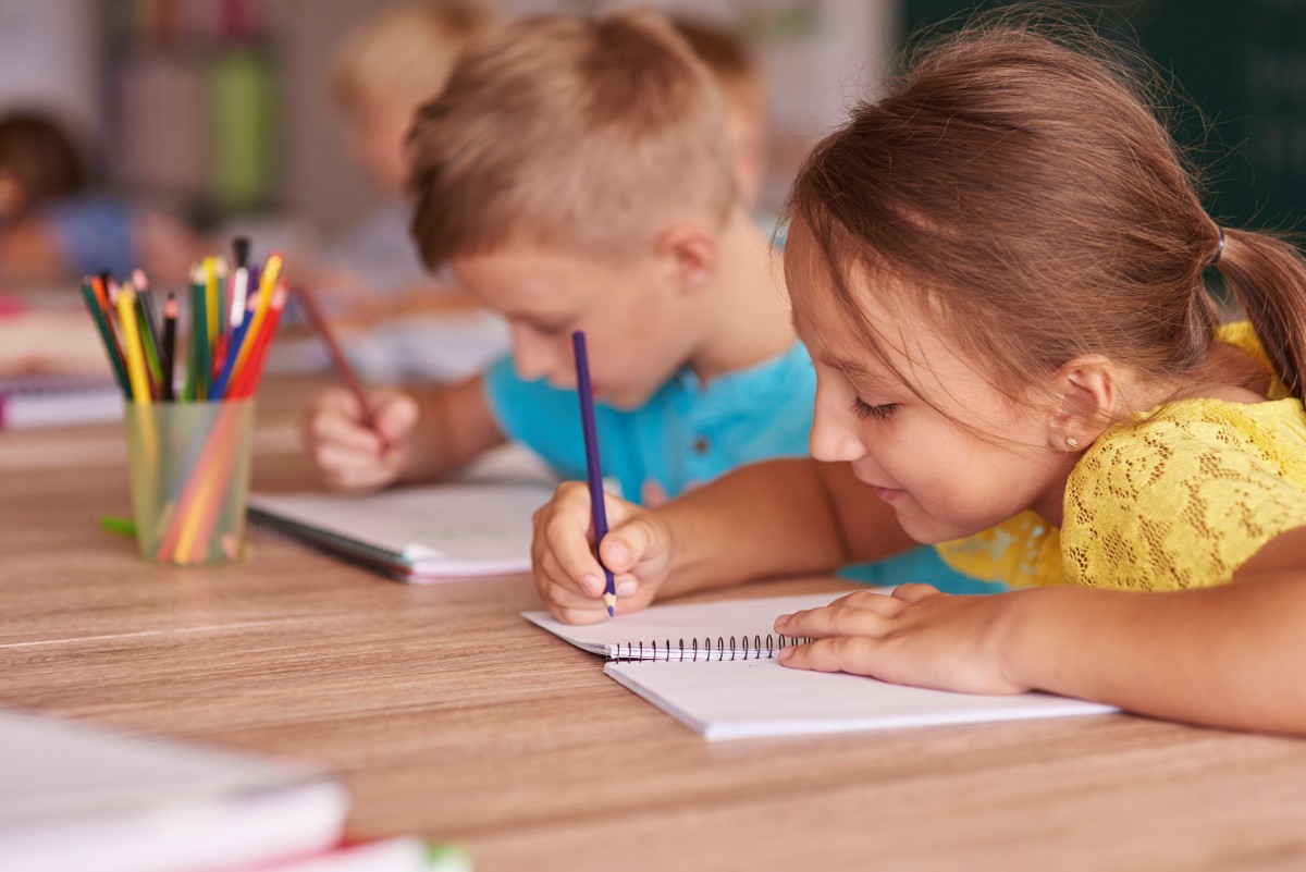Niño y niña pintando en un cuarderno