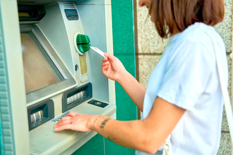 Una mujer utiliza una tarjeta para sacar dinero en un cajero automático