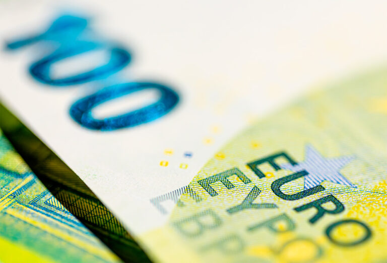 Primer plano de billetes de euro superpuestos, con "100" y "EURO" en foco, lo que sugiere la influencia del BCE en los futuros tipos de interés.