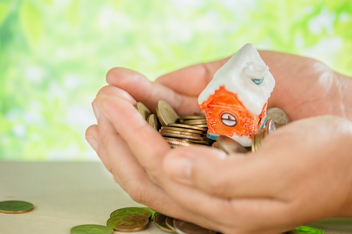 Manos que sostienen dinero y una casa y simbolizan las ayudas para pagar la hipoteca
