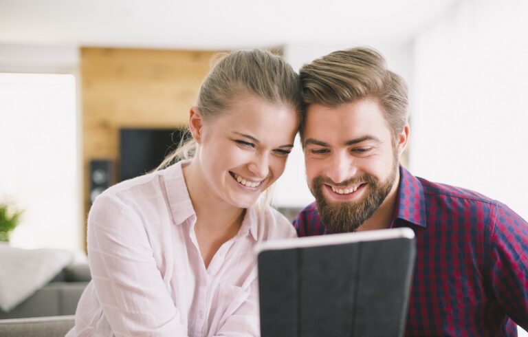 Una pareja sonriente al leer la noticia de que baja el euríbor de diciembre de 2024.