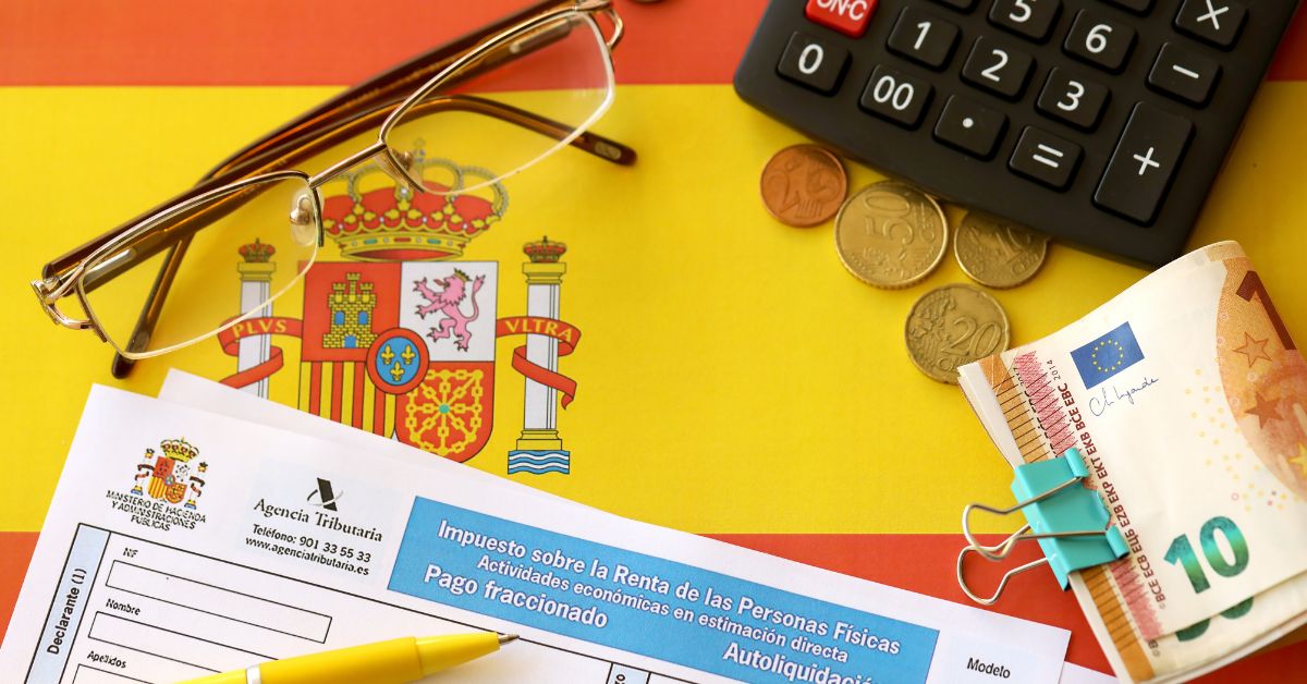 Formulario de impuestos español Modelo 720 con gafas, monedas, calculadora y billetes de euro sobre un fondo colorido con una bandera española.