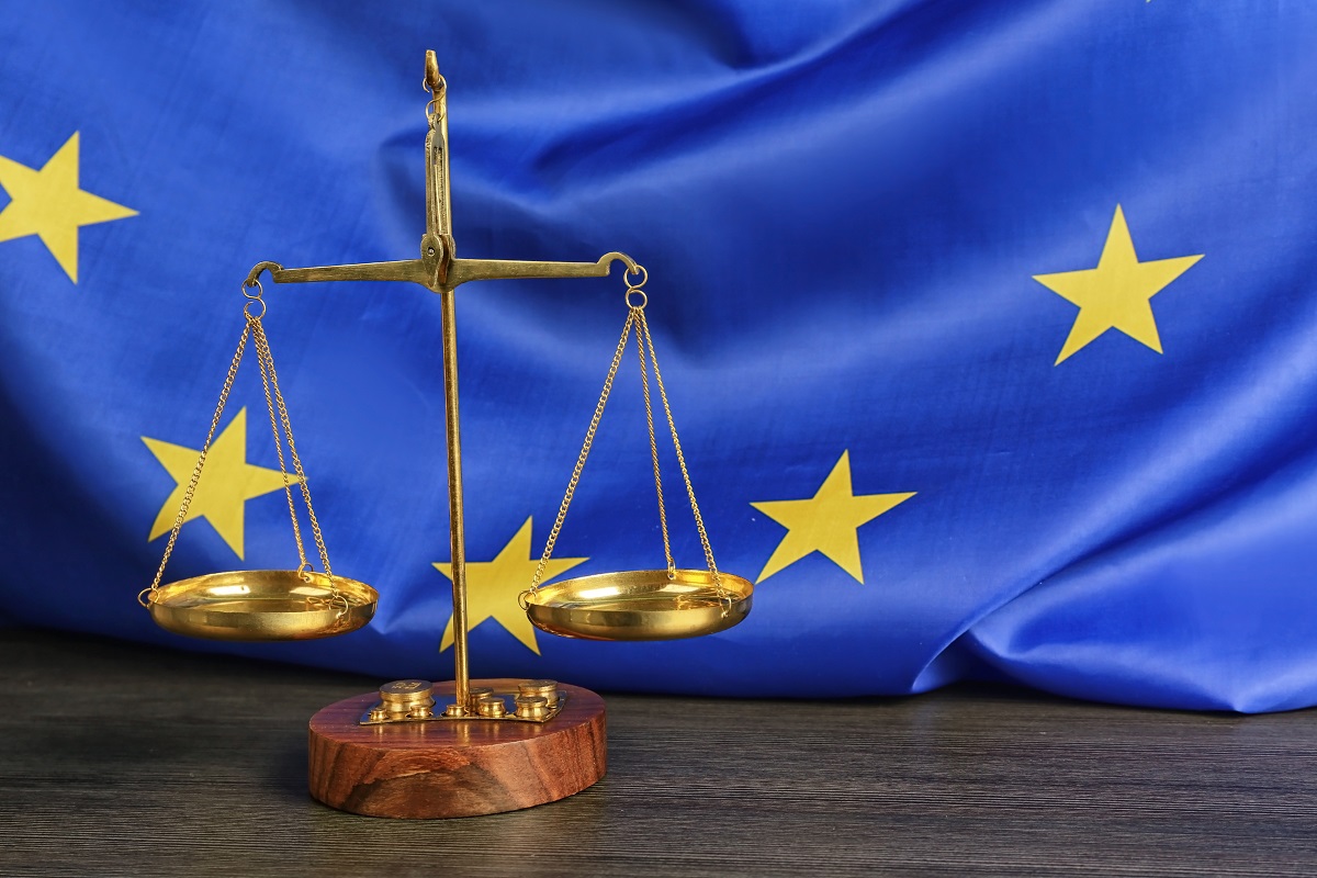Una balanza dorada delante de una bandera de la UE con estrellas amarillas sobre fondo azul, que simboliza la justicia europea en casos relacionados con hipotecas y comisiones de apertura.