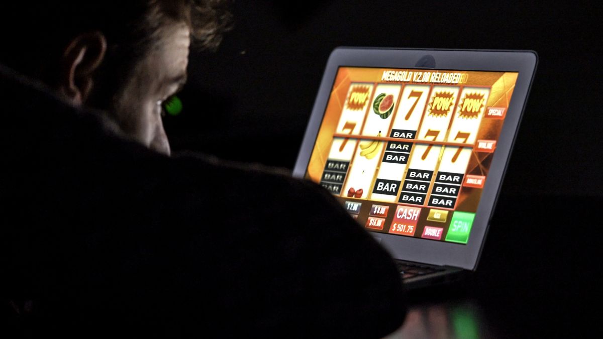 Una persona se sienta frente a la pantalla de su computadora portátil, que muestra un brillante juego de apuestas en línea en un casino virtual.