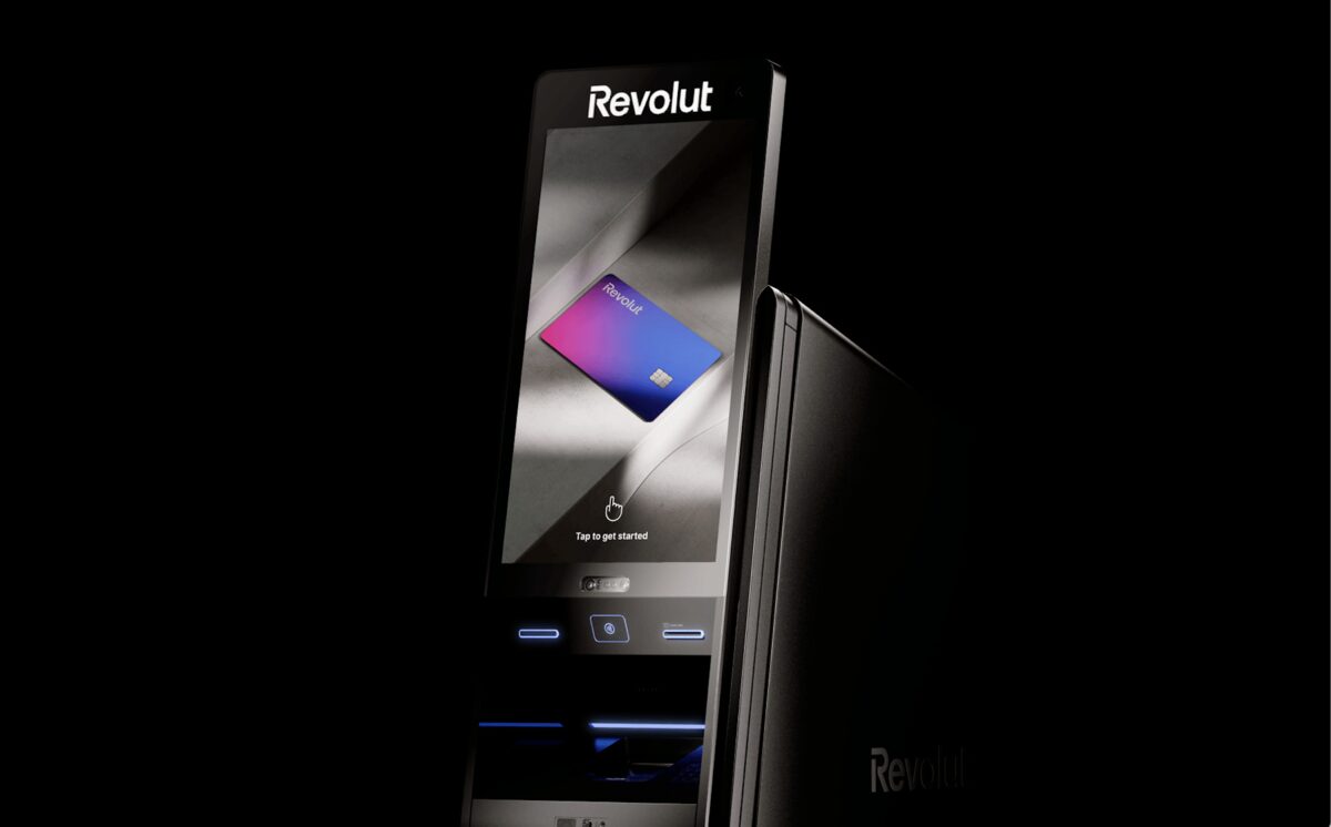 Un cajero automático de la marca Revolut en España con una pantalla táctil que muestra una tarjeta Revolut y el mensaje "Toca para comenzar", lo que resalta la creciente red de cajeros para los usuarios de Revolut.