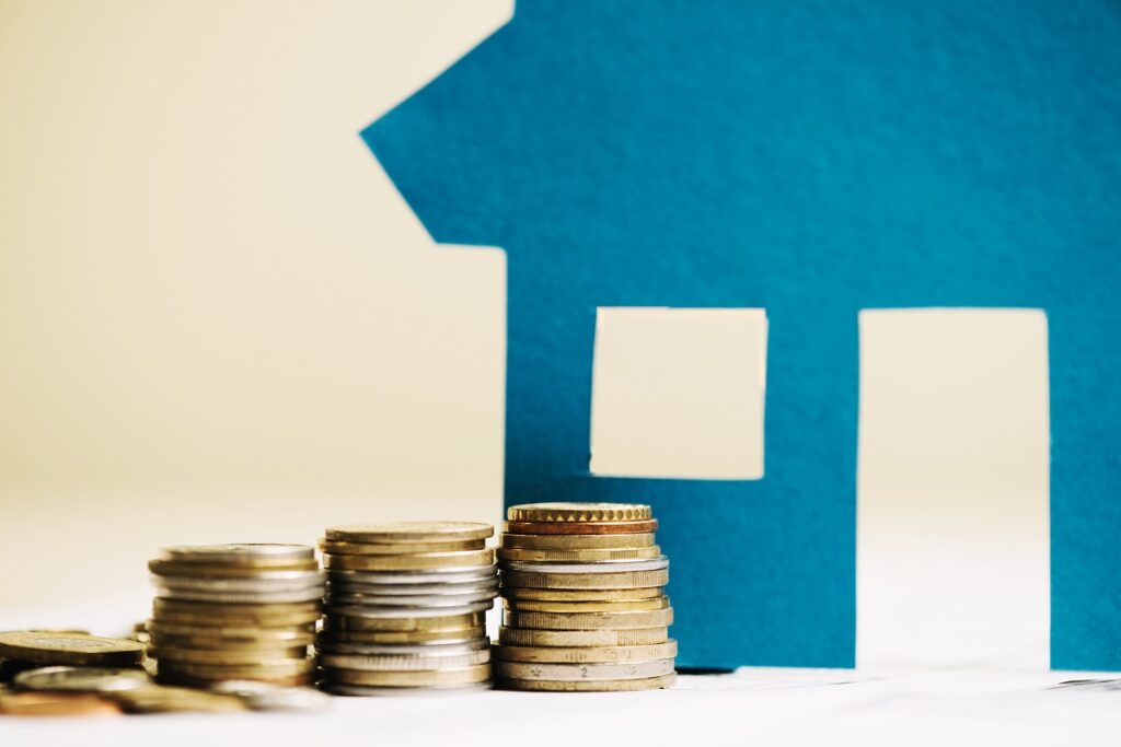 Montón de monedas frente a una vivienda que representa la subida del euríbor