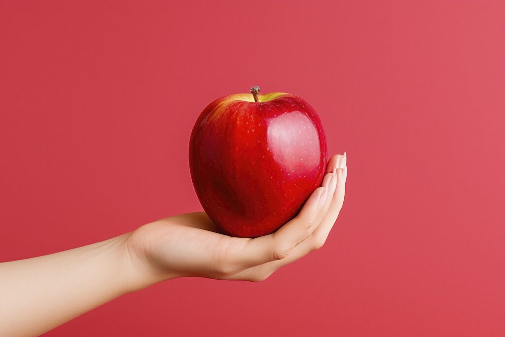 Una mano sostiene una manzana roja brillante sobre un fondo rojo rosado sólido, que simboliza las opciones frescas que tiene al considerar cambiar de banco para su hipoteca.