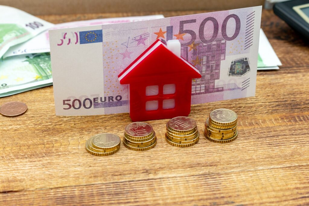 Casa con monedas y billetes que representan el precio de las viviendas